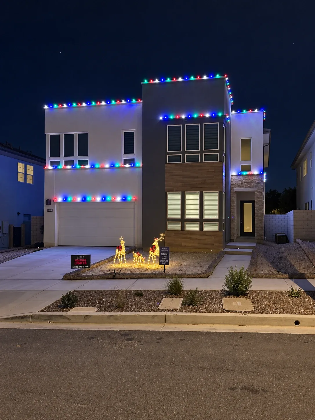 Modern two-story home with multicolor Christmas lights and an Aurix Holiday Lights yard sign