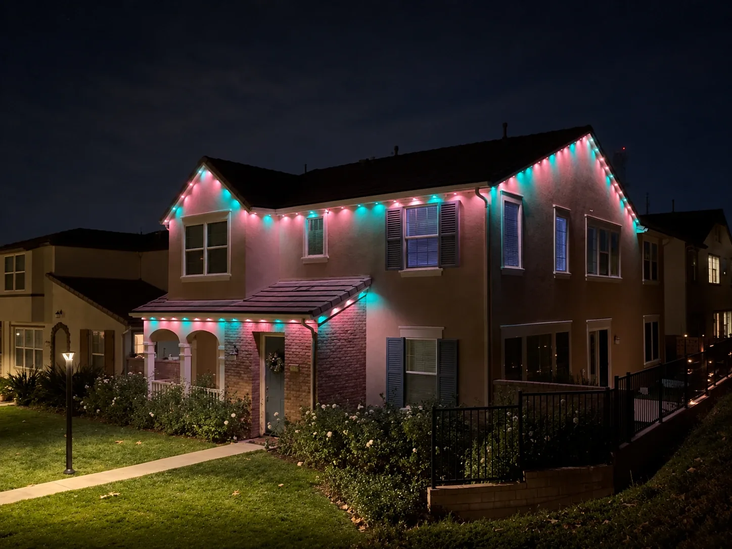 Two-story home with pink and teal Aurix permanent roofline lighting